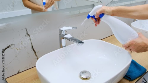 woman doing chores in bathroom at home, cleaning sink and faucet with spray foam detergent wipe microfiber sponge disinfecting housekeeping concept