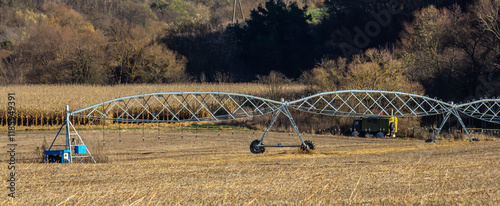 Agricultural irrigation system in operation across a rural landscape with drying crops photo