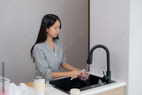 Woman cleaning breast pump in kitchen sink