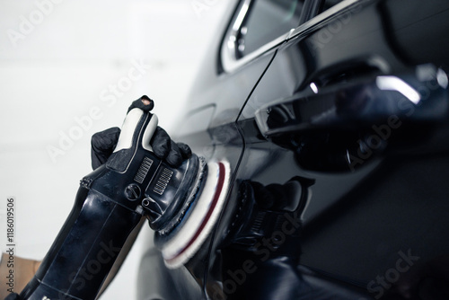 Close up view of brush grinder polishing car paint inside repair shop.