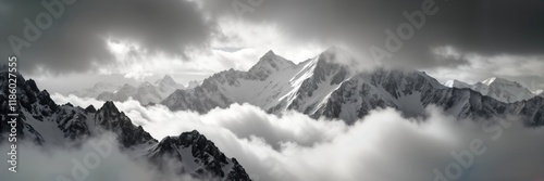 Majestic snow-capped mountains rise above dense clouds. Panoramic view rugged peaks, slopes. Winter landscape. High altitude. Dramatic clouds. Nature beauty. Extreme scenery. Sunny day. Excellent for