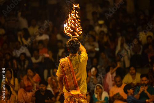 Ganga aarti, Portrait of young priest performing holy river ganges evening aarti at assi ghat in traditional dress with hindu rituals. photo