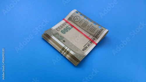 Принти на полотні Small bundle of few five hundred rupee indian currency bank note isolated on blue table background with copy space