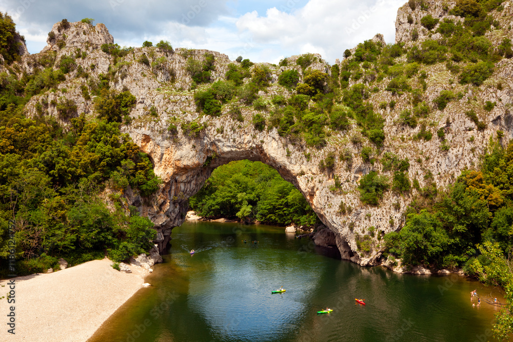 Naklejka premium Canoes below the natural stone arch Pont d'arc across the Ardèche river