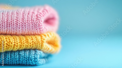 Soft knitted sweaters in pastel shades are neatly arranged on a blue surface, offering a cozy and inviting look for cooler days