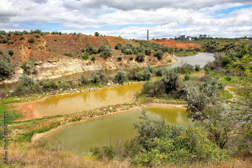 Lush riverbanks with rich vegetation under dramatic cloud patterns by the water's edge