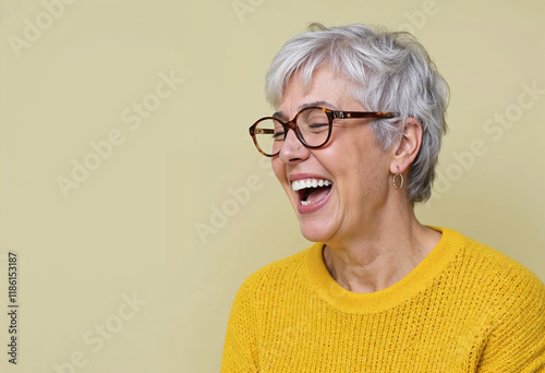 Portrait of happy gray-haired old woman in yellow sweater laughing
