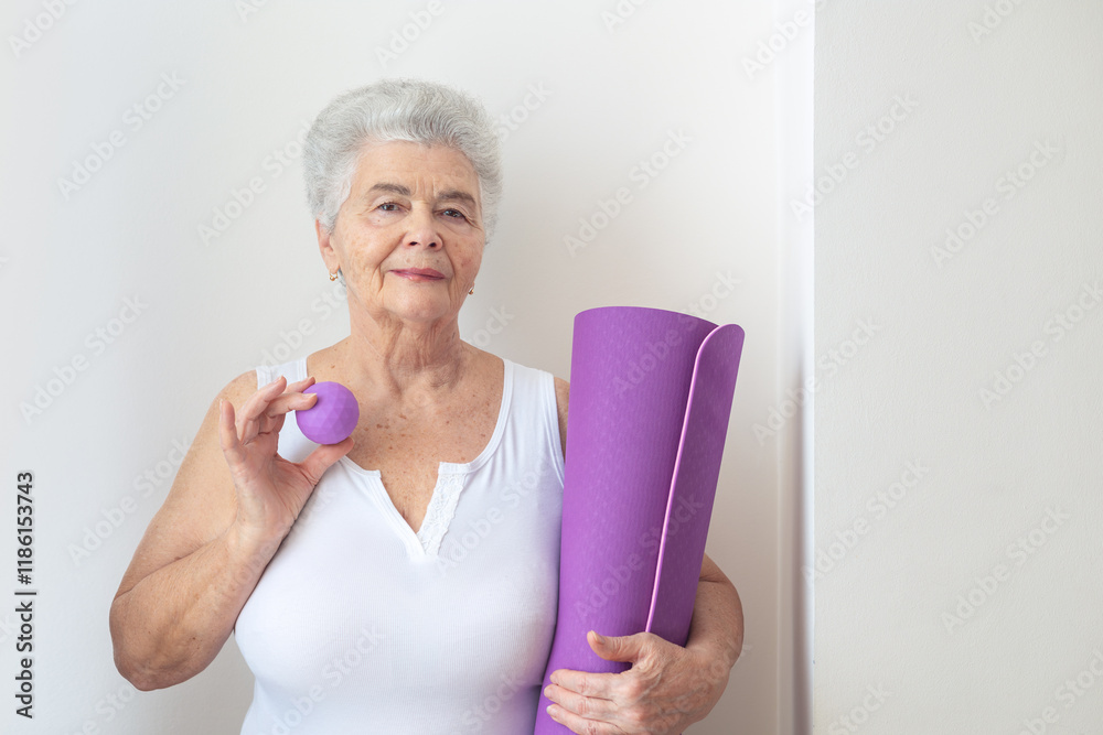 Senior woman holding a yoga mat and massage ball, promoting physical health, fitness, and rehabilitation. Concept of staying active, recovery, and maintaining mobility for mental and physical well-bei Senior woman holding a yoga mat and massage ball, promoting physical health, fitness, and rehabilitation. Concept of staying active, recovery, and maintaining mobility for mental and physical well-bei