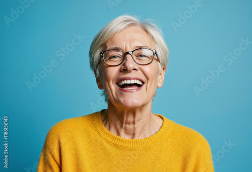 Portrait of a gray-haired mature woman in a yellow sweater on a blue background