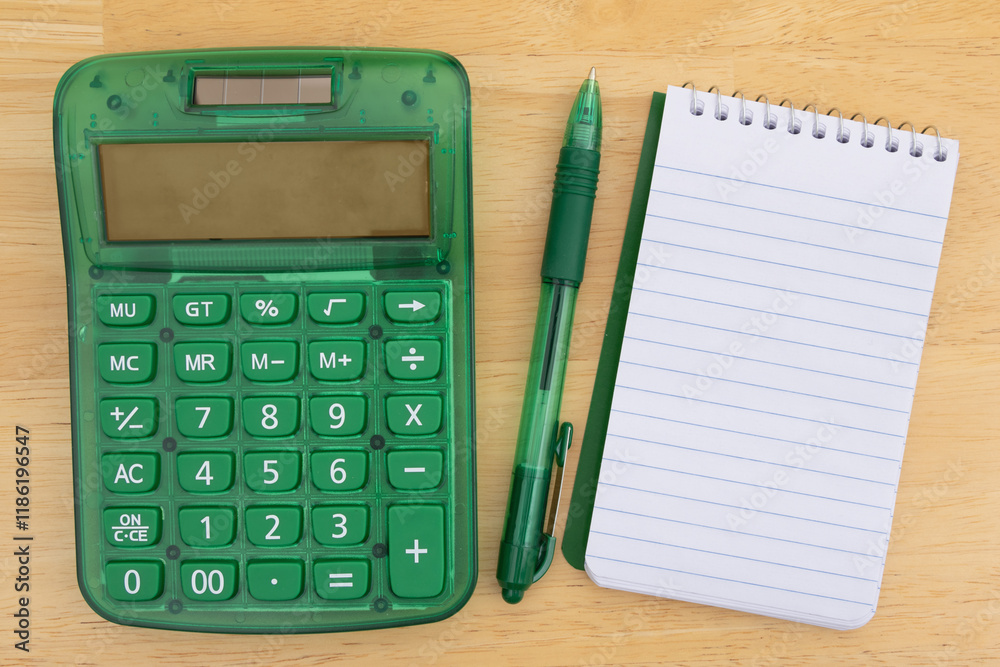 Green calculator, pen, and notebook on wooden desk Green calculator, pen, and notebook on wooden desk