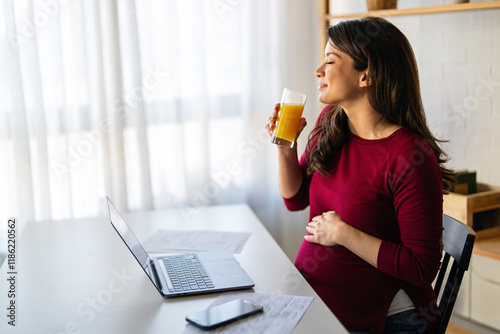 A confident mid adult pregnant woman having an online conference video call with her colleagues