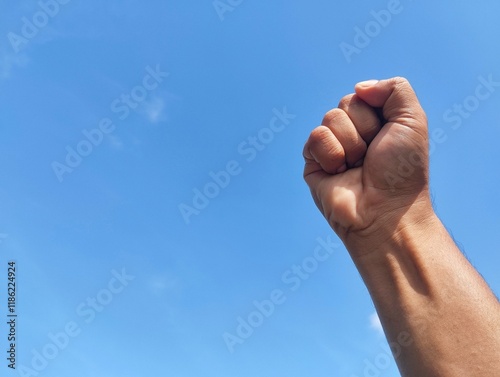 Foto Close-up of hand punching the air against a bright blue sky