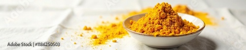 A small pile of turmeric powder in a shallow dish on a white tablecloth, powder pile, background, yellow