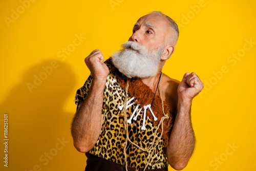 Photo of ancient aged caveman terrified look empty space wear leopard skin clothes isolated on yellow color background photo