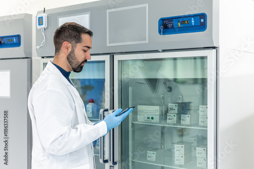 Scientist using tablet checking refrigerated drugs in pharmaceutical laboratory refrigerator photo