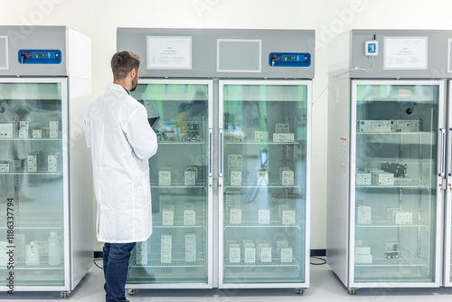 Scientist checking medical refrigerators storing drugs and vaccines in pharmaceutical laboratory