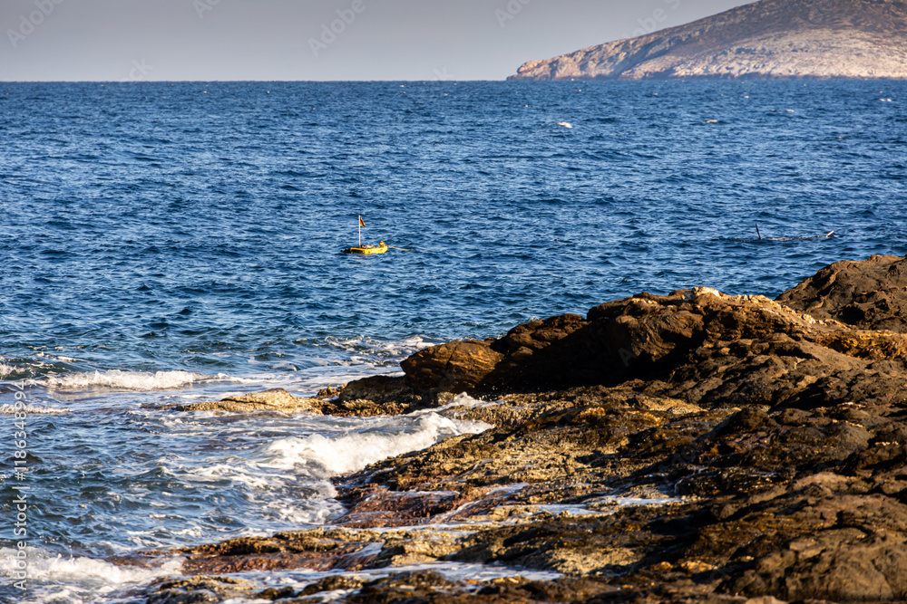 Diving in Mediterranean sea. Photo with a diver swimming under water with a diving tank next to it.