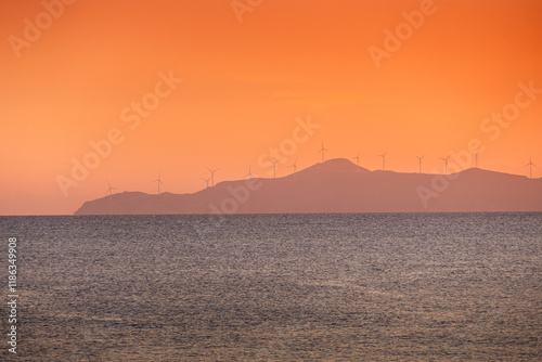Obraz na płótnie Wind turbines sunset. Seaside landscape with a wind turbine farm on a mountain. Green energy electricity source. Concept image for eco energy. w salonie