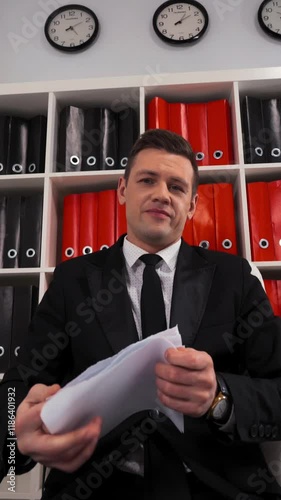 Angry handsome businessman tearing up a document, contract or agreement with You sitting in office armchair. Paper pieces. Termination docs with clients by company concept. Vertical Shot. photo