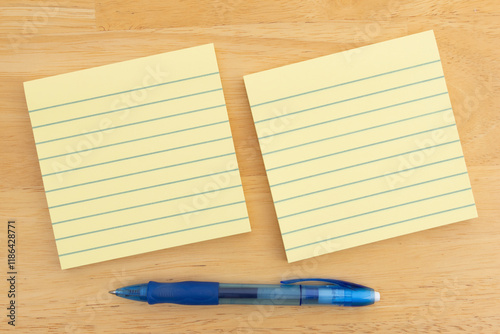 Fotografía Yellow sticky notes and blue pen on wooden table