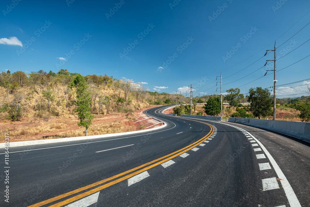Long curvy forest asphalt road over the hills. Beautiful curved road in the forest. Side view of road Long curvy forest asphalt road over the hills. Beautiful curved road in the forest. Side view of road
