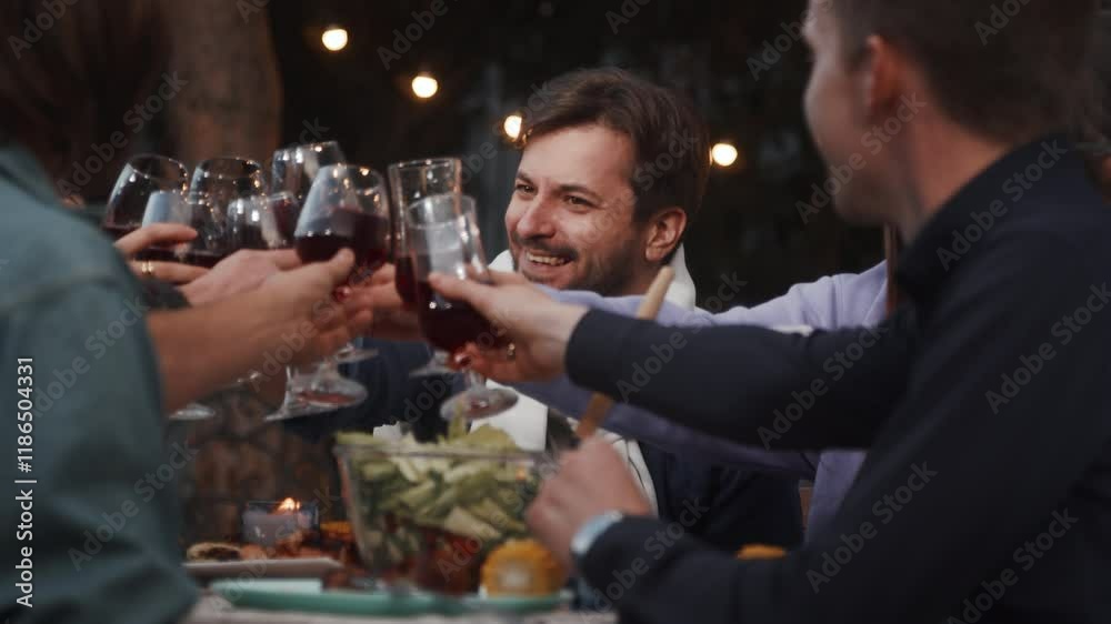 Friends raising glasses of red wine during a festive outdoor dinner Friends raising glasses of red wine during a festive outdoor dinner