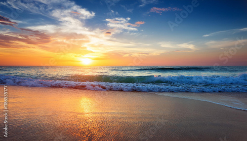 a colourful sunset over gentle ocean waves with a sandy beach