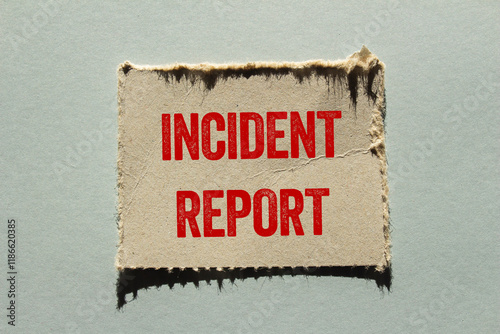 Incident report message written on ripped torn paper piece on gray background. Conceptual incident report symbol. Copy space.