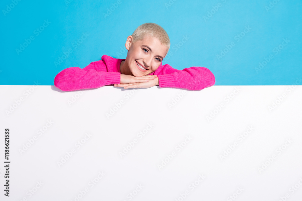 Charming young woman with blond short hair and a vibrant pink sweater leaning on a white surface Charming young woman with blond short hair and a vibrant pink sweater leaning on a white surface