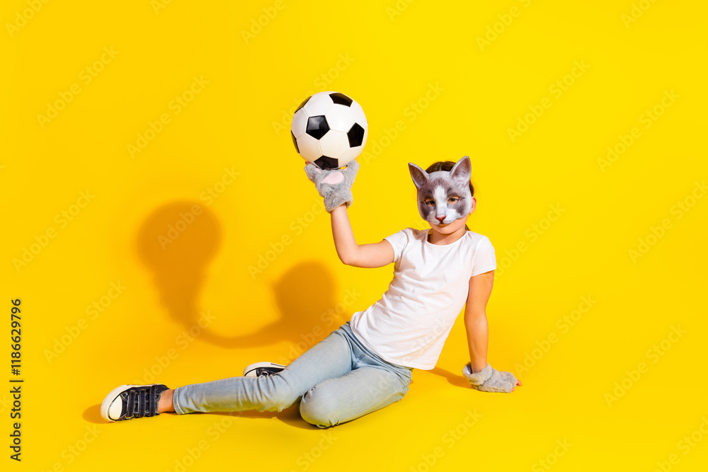 Young girl in playful quadrobist disguise holding a soccer ball on vibrant yellow background showcasing creativity and fun Young girl in playful quadrobist disguise holding a soccer ball on vibrant yellow background showcasing creativity and fun