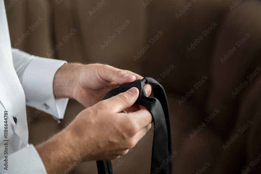 A man is getting ready to tie his tie. He is wearing a white shirt and is holding the tie in his hands A man is getting ready to tie his tie. He is wearing a white shirt and is holding the tie in his hands