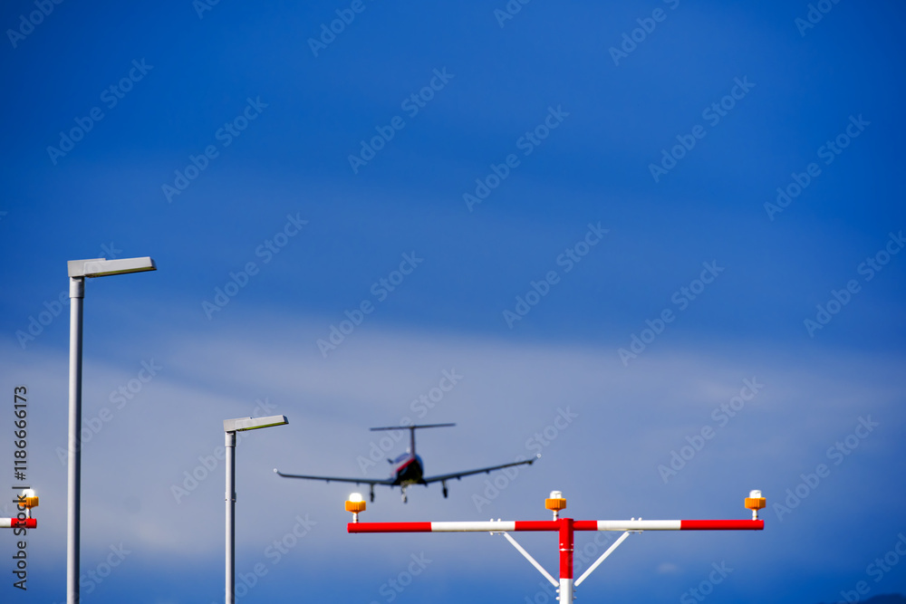 Fototapeta premium Street light and beacon with propeller airplane landing at Swiss Airport Zürich Kloten on a winter day. Photo taken January 9th, 2025, Zurich Kloten, Switzerland.