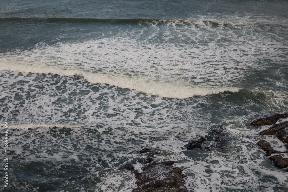Obraz premium Ocean waves crashing over rocky shoreline