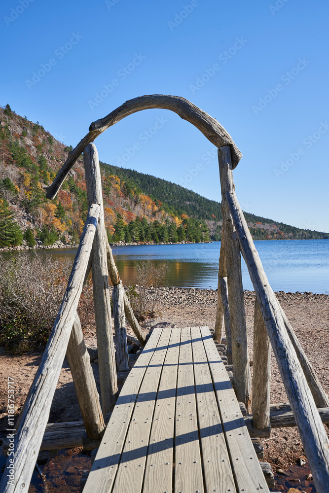 A rustic bridge near Jordan's Pond in Acadia National Park. It is a sunny autumn day, and the fall colors are seen on the side of the mountain in the distance. A rustic bridge near Jordan's Pond in Acadia National Park. It is a sunny autumn day, and the fall colors are seen on the side of the mountain in the distance.