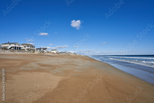 Fototapeta Naklejka Na Ścianę i Meble -  Seabrook beach during off-season in October. It is a sunny day on the sandy beach, but there are no people to be seen. A row of vacation cottages line the beach.