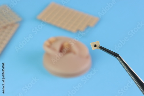 Close up view of the Auriculotherapy Seeds in a clip with others itens in the background - back view of the sticker 