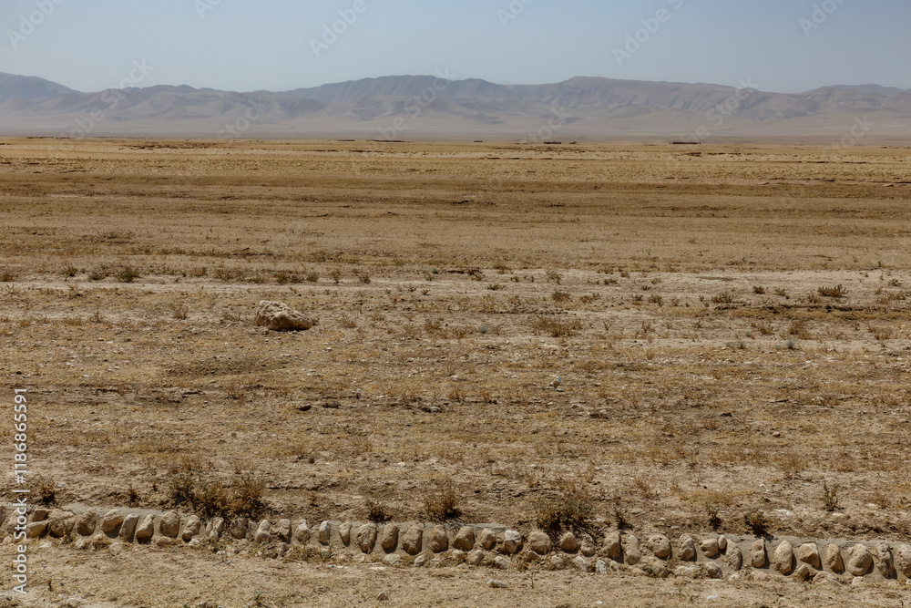Vast arid landscape in Kunduz Province Afghanistan with sparse vegetation and distant hills Vast arid landscape in Kunduz Province Afghanistan with sparse vegetation and distant hills
