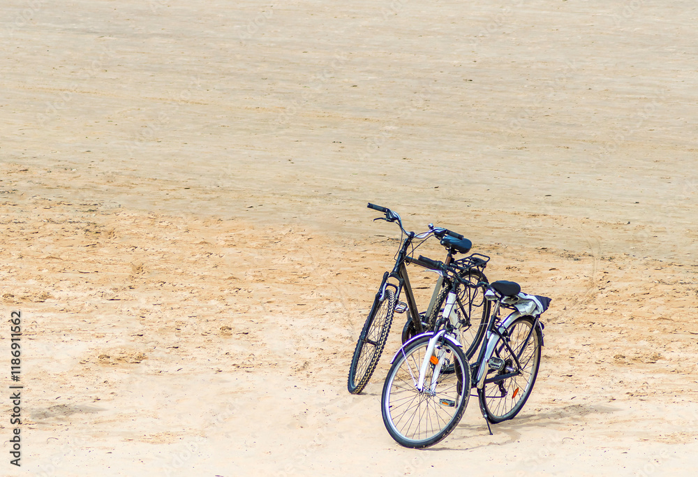 Fototapeta premium Couple of bicycles at sandy beach of the Baltic Sea in Jurmala - famous tourist resort in Latvia at summer season. Healthy and sport life style concept. No AI tools were used