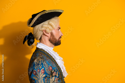 Side profile of a man dressed in a historical nobleman costume with an orange background
