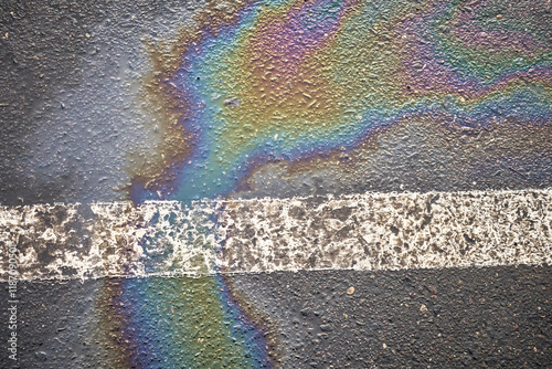 Damp asphalt in a parking area, displaying a fuel spill from a car, bordered with a white line. photo