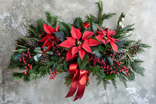 A festive holiday bouquet with red poinsettias, holly berries, and evergreen branches, with a red ribbon. photo