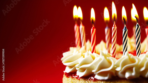 Festive birthday cake with lit striped candles and creamy frosting on a vibrant red background, perfect for celebratory designs, invitations, and greeting cards