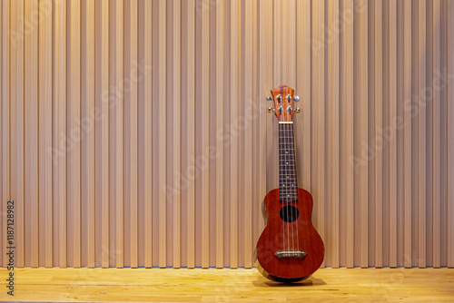 Selective focus of Ukulele with wooden wall, The Uke is a member of the lute family of instruments of Portuguese origin and popularized in Hawaii, Lath wood texture with vertical lines as background photo