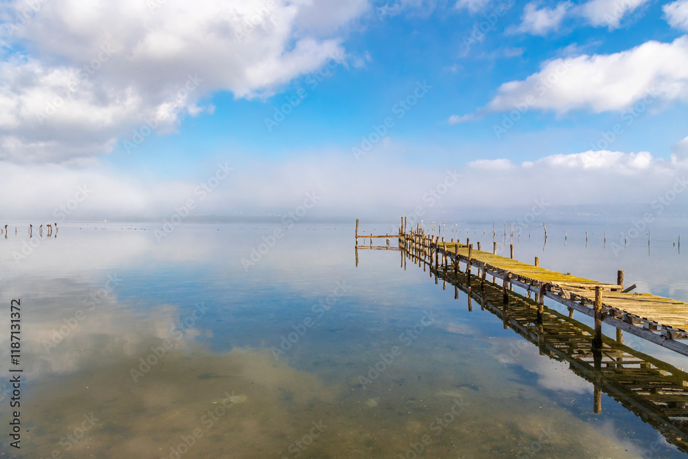 Wooden pier in mist with reflection