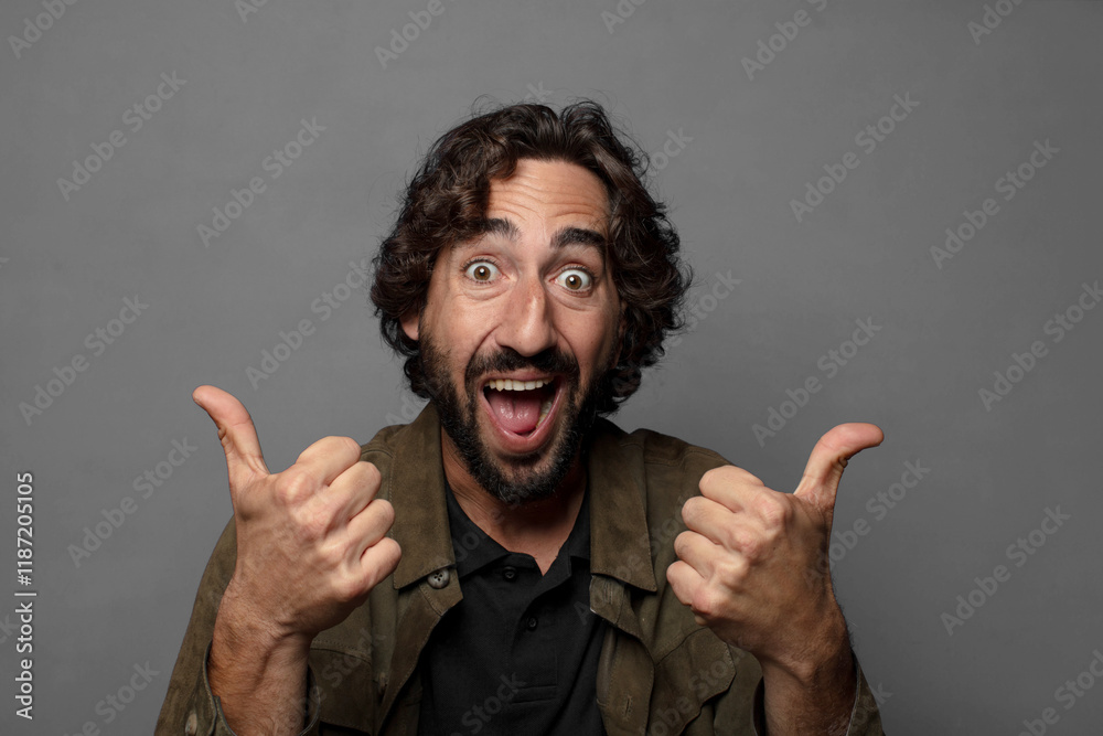 Fototapeta premium smiling joyfully and looking happy, feeling carefree and positive with both thumbs up