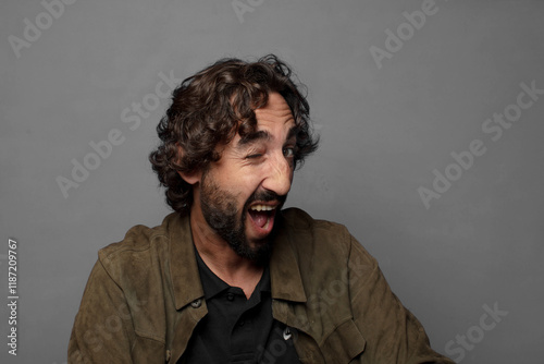 looking happy and friendly, smiling and winking an eye at you with a positive attitude