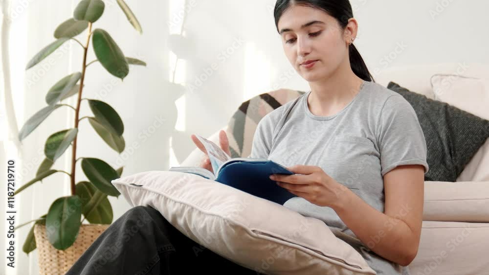 Woman sitting on sofa indoor reading textbook increase knowledge about social and technology for occupation or raise children to be good adult as smart mother. Lifelong learning concept. Divergence.