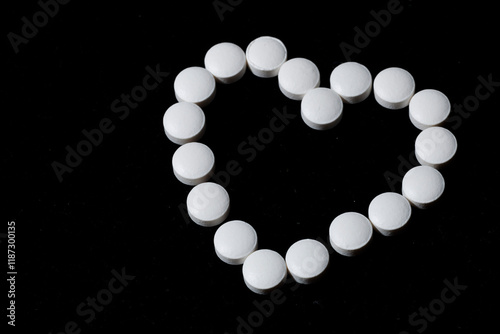 White round tablets are scattered on a black background.