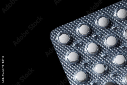 White round tablets are scattered on a black background.