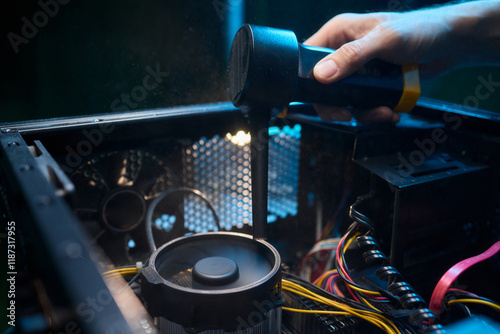 A man cleans a computer case with a vacuum in a bright room, stressing workspace tidiness